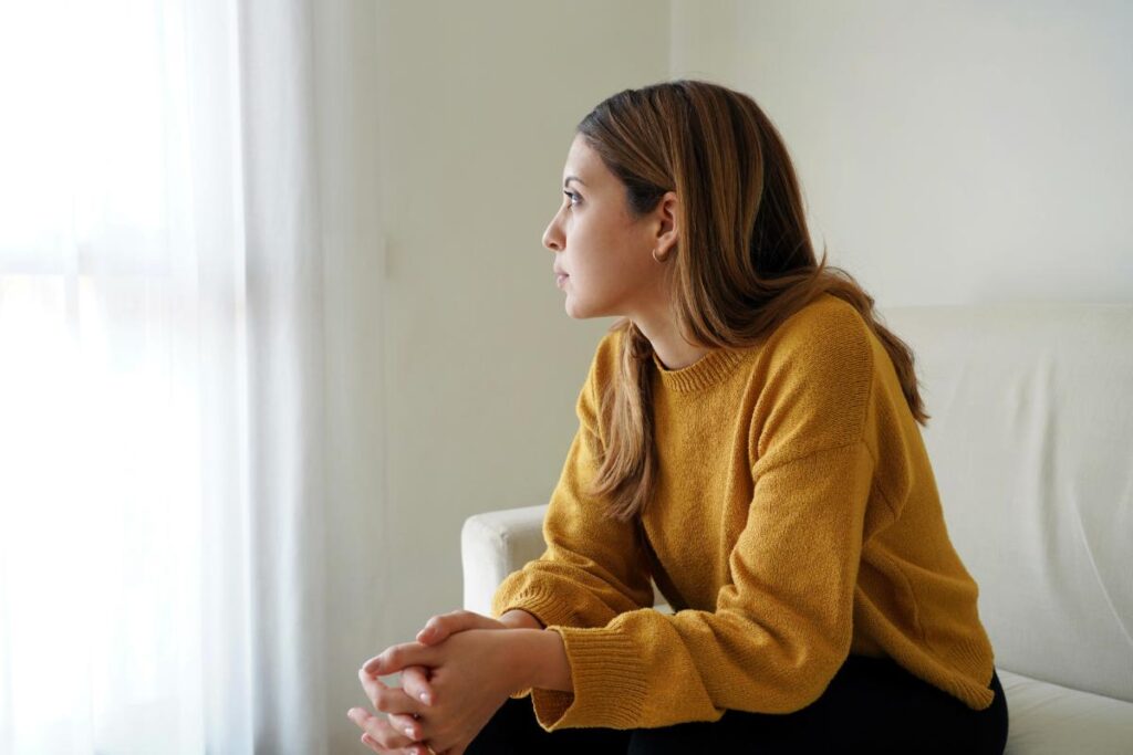 a person sits on the couch and looks out the window learning about coping with seasonal depression