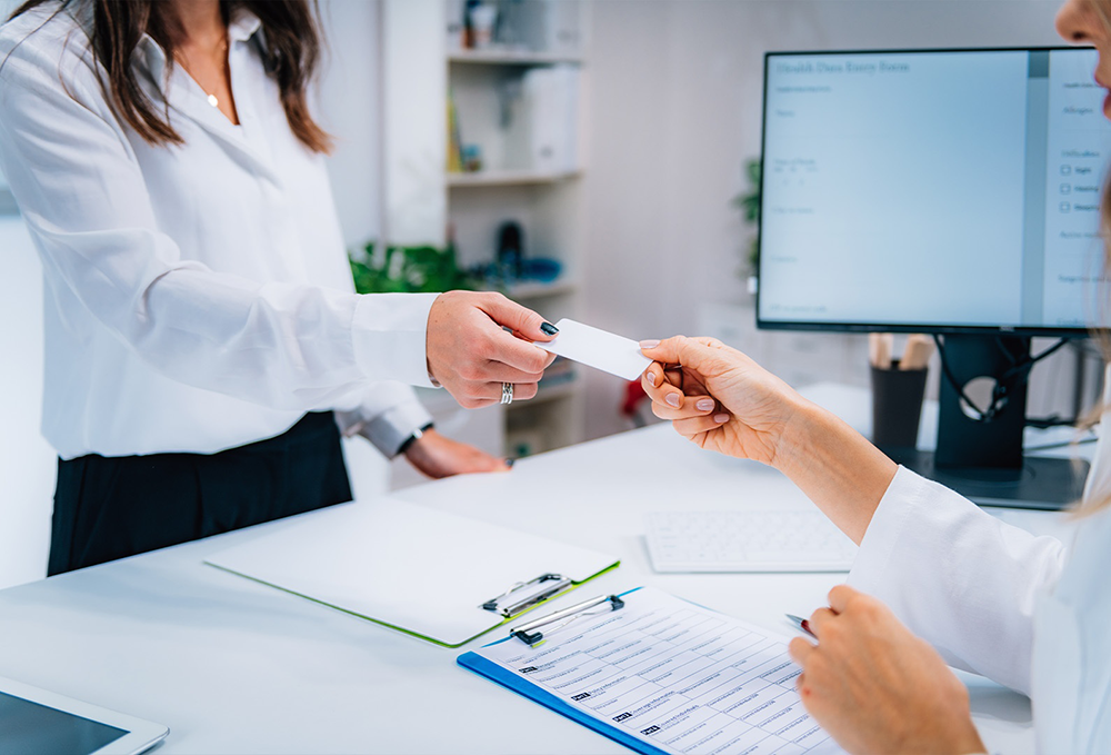 A woman accepting an insurance card at Arkview Behavioral Health